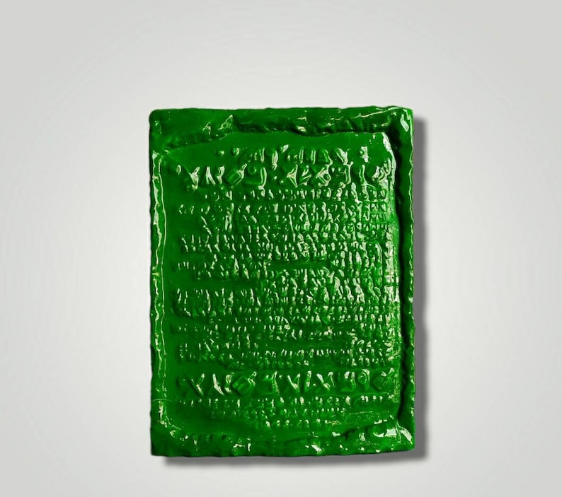 Op de afbeelding: Een groene keramische plaquette met een reli&euml;f, getextureerd oppervlak. De plaquette heeft een ontwerp van een herhalend patroon van letters en symbolen.