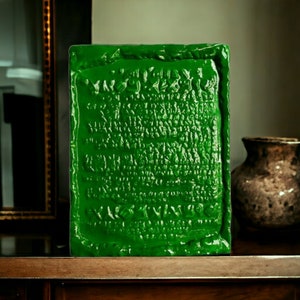 Op de afbeelding: Een groene rechthoekige plaquette met reli&euml;fletters in een oud schrift. De plaquette is gemaakt van een glad, glanzend materiaal en heeft een licht getextureerd oppervlak.