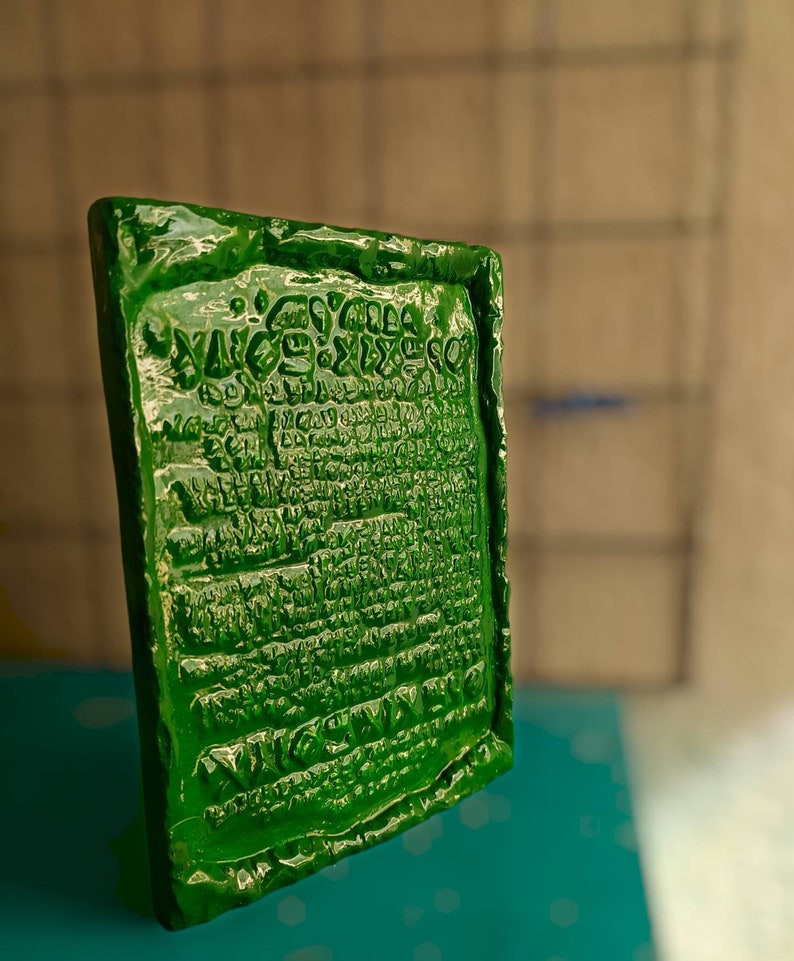 Op de afbeelding: Een groene rechthoekige plaquette met reli&euml;fletters. De letters zijn in een oude taal en bevatten het woord "VICTORY".