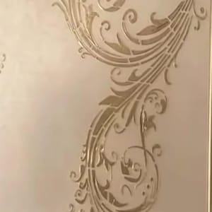 Pode incluir: Painel decorativo de parede com um design floral dourado e ornamentado. O design inclui padrões em espiral, folhas e elementos florais estilizados, criando uma estética elegante e clássica. O painel está sobre um fundo claro.