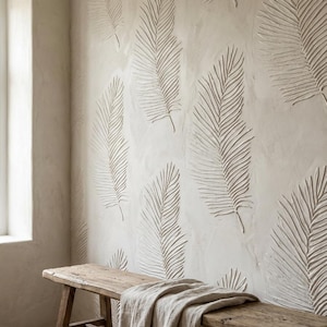 Könnte beinhalten: Eine strukturierte Wand mit einem sich wiederholenden Muster aus geprägten Palmenblättern in einer neutralen Farbe. Im Vordergrund befindet sich eine Holzbank mit einem Leinentuch. Das Wanddesign fügt dem Raum ein natürliches, organisches Element hinzu.