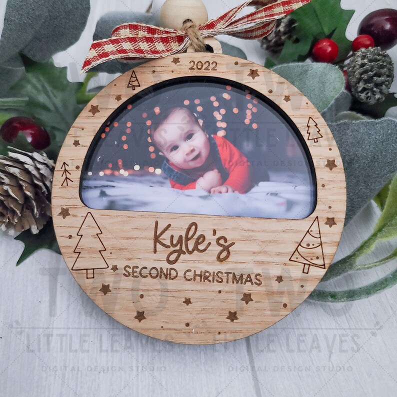 K&ouml;nnte beinhalten: Ein h&ouml;lzerner Weihnachtsbaumschmuck mit einem Fotorahmen, einem Sternendesign und dem Text "2022 Kyle's Second Christmas".
