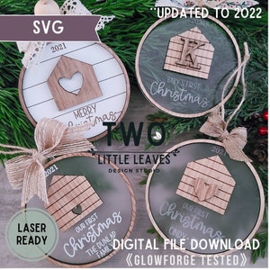 Könnte beinhalten: Vier lasergeschnittene Weihnachtsbaumschmuck-Designs mit einem Haus mit einem Herzen, dem Text "Merry Christmas", "Baby's First Christmas", "Our First Christmas" und "Our First Christmas" mit dem Text "The Dunlap Family". Die Ornamente sind aus Holz und haben einen transparenten Acryl-Hintergrund. Der Text "Updated to 2022", "Two", "Little Leaves Design Studio", "Laser Ready", "Digital File Download" und "Glowforge Tested" sind ebenfalls im Bild enthalten.