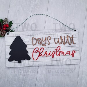 May include: White wooden sign with a black chalkboard tree, brown wooden letters spelling "Days until Christmas" and red letters spelling "Christmas". The sign has a green and white twine hanger.