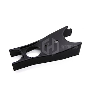 Può includere: Un oggetto nero stampato in 3D con un design curvo unico. Presenta diverse aperture circolari e rettangolari, e il testo "HYPERFIL3D" è visibile. L'oggetto sembra essere un componente o un pezzo.