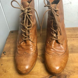 May include: A pair of brown leather lace-up ankle boots with a brogue design.