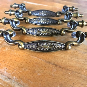 May include: Set of five antique brass cabinet drawer pulls with ornate floral designs.