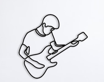 May include: A black line drawing of a person playing an electric guitar. The drawing is on a white wall above a light gray couch.