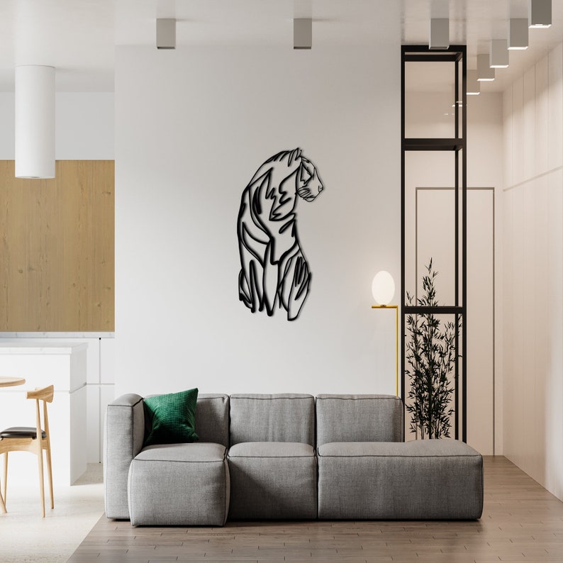 May include: Black metal wall art featuring a stylised tiger in profile. The tiger is facing to the right and is outlined in a single line. The art is mounted on a white wall in a modern living room setting.