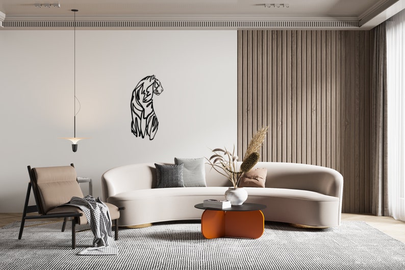 May include: A modern living room interior with a white sofa, a black and white line art tiger wall decor, a wooden slat wall, a black and orange coffee table, and a brown armchair with a throw blanket.