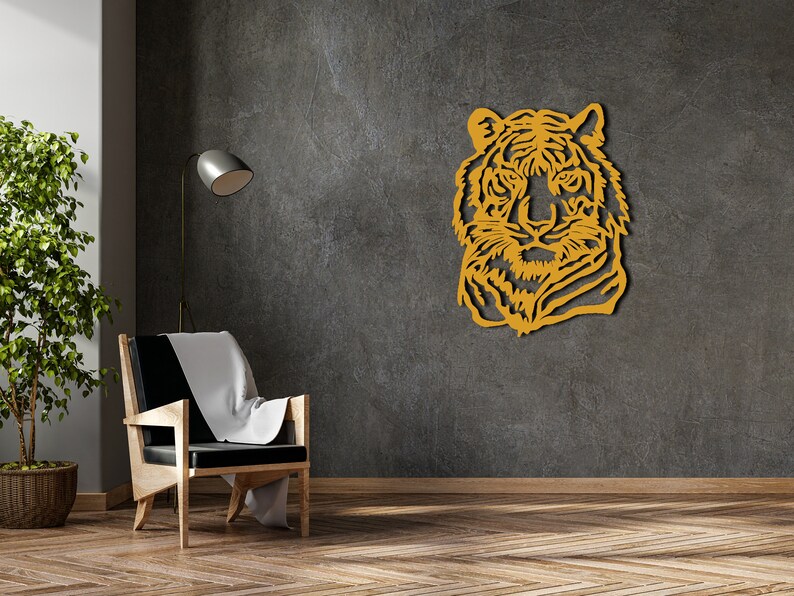 May include: A wooden wall decor featuring a tiger's head in a yellow-gold color. The tiger's head is facing forward with a serious expression. The decor is mounted on a gray textured wall.