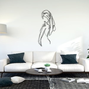 May include: A black metal wall sculpture of a person with a towel wrapped around their head. The sculpture is mounted on a white wall in a living room setting.