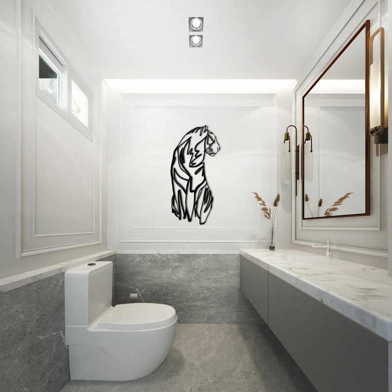 May include: A black and white stylised silhouette of a tiger on a white wall in a bathroom. The tiger is facing to the right and is in a standing position. The bathroom has a white toilet and a grey countertop with a sink.