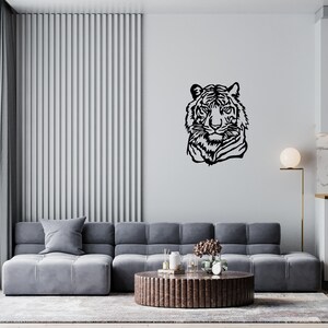 May include: A black and white line art illustration of a tiger's head, mounted on a white wall in a living room setting. The tiger's head is facing forward, with its mouth closed and its eyes open. The illustration is simple and elegant, and it would make a great addition to any home decor.