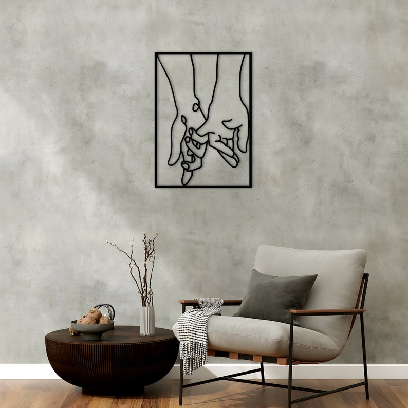 May include: Black metal wall art depicting two hands holding each other. The hands are outlined in black and are set against a white background.
