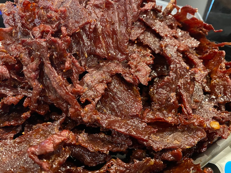 Puede incluir: Primer plano de un mont&oacute;n de cecina de ternera marr&oacute;n oscuro. La cecina es fina y tiene un acabado brillante.