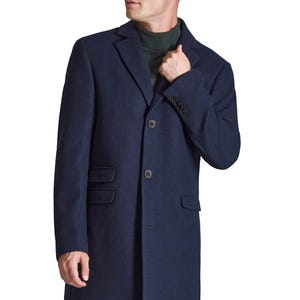 May include: A navy blue overcoat with a classic design. The coat features a notched lapel, two front pockets, and a two-button closure. The sleeves have button details. The person is wearing a green turtleneck underneath.