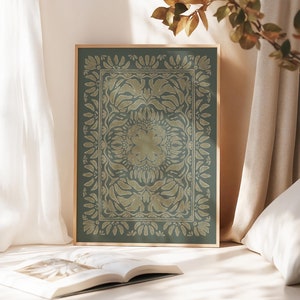 May include: A framed print with a green background and a gold floral pattern. The pattern is symmetrical and has a mandala-like design.
