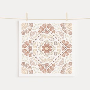 May include: A square print with a brown and beige geometric pattern. The pattern is symmetrical and features a floral design in the center.