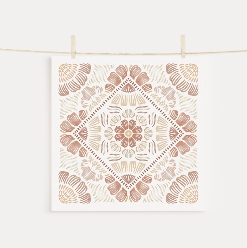 May include: A square print with a brown and beige geometric pattern. The pattern is symmetrical and features a floral design in the center.