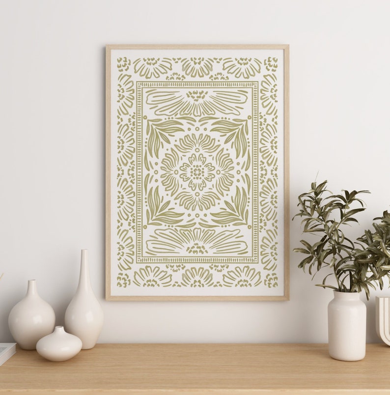 May include: A framed print with a green and white geometric pattern of stylized flowers and leaves. The print is in a light wood frame and is hanging on a white wall.