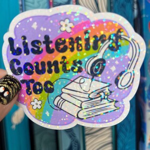 May include: A sparkly purple sticker with a rainbow design and the text "Listening Counts Too" with a stack of books and headphones.