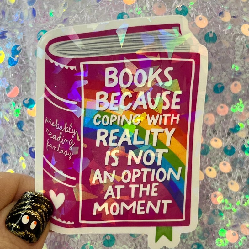 May include: A sticker with a book design in shades of pink and white. The text reads "BOOKS BECAUSE COPING WITH REALITY IS NOT AN OPTION AT THE MOMENT." A rainbow and the words "probably reading fantasy" are also visible.