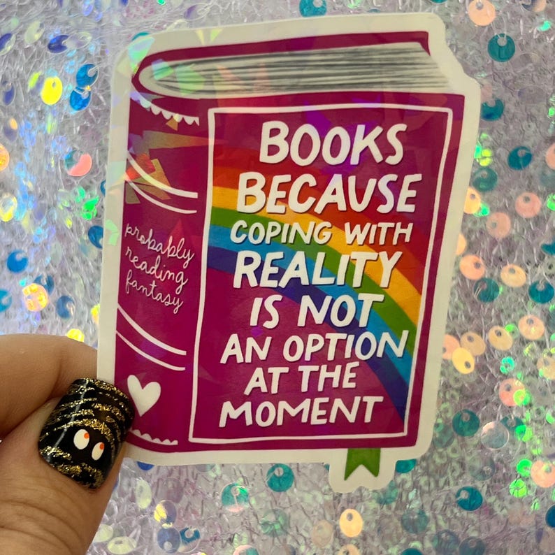 May include: A sticker in the shape of a book with the text "BOOKS BECAUSE COPING WITH REALITY IS NOT AN OPTION AT THE MOMENT." The sticker has a rainbow design and the words "probably reading fantasy."