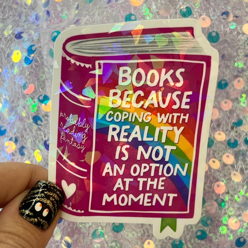 May include: A sticker with a book design in shades of pink and purple. The text reads "BOOKS BECAUSE COPING WITH REALITY IS NOT AN OPTION AT THE MOMENT." A rainbow gradient is visible.