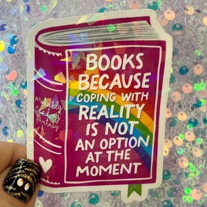 May include: A sticker in the shape of a book with the text "BOOKS BECAUSE COPING WITH REALITY IS NOT AN OPTION AT THE MOMENT." The sticker has a rainbow design and the words "probably reading fantasy".