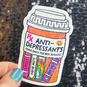 May include: A sticker in the shape of a prescription pill bottle with the words "ANTI-DEPRESSANTS" and "(TAKE DAILY FOR BEST RESULTS)". The bottle has a smiley face and the words "SMUT", "SLOW BURN", "Romantasy", and "ROMANCE" on the labels.