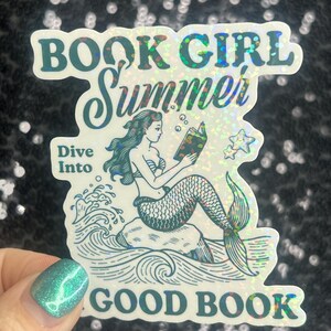 Może przedstawiać: Holograficzna naklejka z napisem "BOOK GIRL Summer" i "Dive Into GOOD BOOK". Naklejka przedstawia syrenę czytającą książkę siedzącą na skale, z falami i gwiazdami. Naklejka ma błyszczące, iryzujące wykończenie.