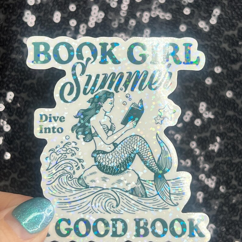 Może przedstawiać: Holograficzna naklejka z napisami "BOOK GIRL Summer" i "Dive Into GOOD BOOK". Naklejka przedstawia syrenę czytającą książkę siedzącą na skale, z bąbelkami i gwiazdami wok&oacute;ł niej.