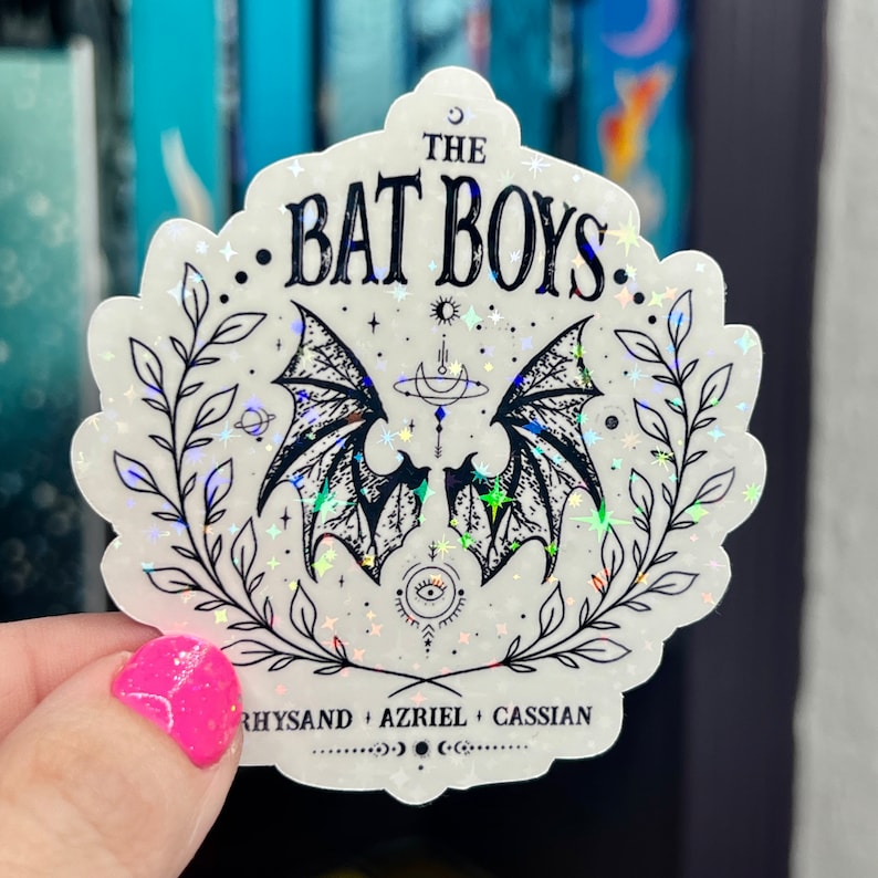 Pu&ograve; includere: Un adesivo bianco con un'illustrazione in bianco e nero di ali di pipistrello, stelle e una luna crescente. Il testo "THE BAT BOYS" &egrave; in cima all'adesivo. Il testo "RHYSAND + AZRIEL + CASSIAN" &egrave; in fondo all'adesivo.