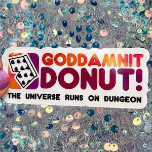 May include: A rectangular sticker featuring a white background with a colorful gradient logo. The text reads GODDAMNIT DONUT! with a graphic of a twenty-sided die containing heart symbols. Below, the text reads THE UNIVERSE RUNS ON DUNGEON.