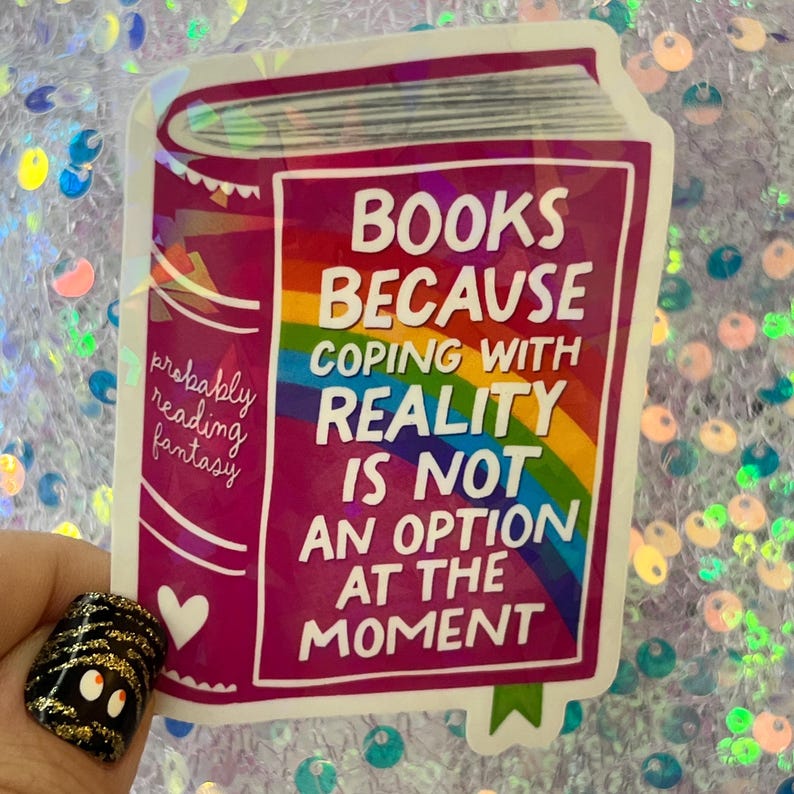 May include: A holographic sticker in the shape of a book with the text "BOOKS BECAUSE COPING WITH REALITY IS NOT AN OPTION AT THE MOMENT." The sticker also includes the phrase "probably reading fantasy" and a rainbow design.