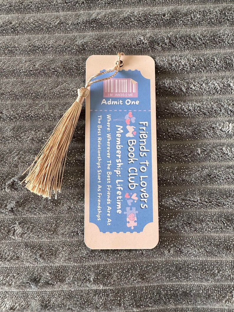 May include: A light blue and pink bookmark with a ticket design. It says "Friends to Lovers Book Club" and "Membership: Lifetime".