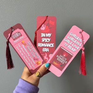 May include: Three pink and red bookmarks with red tassels. The bookmarks feature text that says "Spicy Romance Book Club", "In My Spicy Romance Era", and "Gorgeous Girls Love To Read".