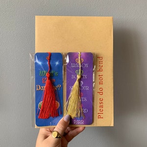 May include: Two purple and blue bookmarks with gold and red tassels. The bookmarks feature text that reads "What's Your Dare?" and "Aragon,  Boelyn, Seymour,  Haves,  Howard, Parr".