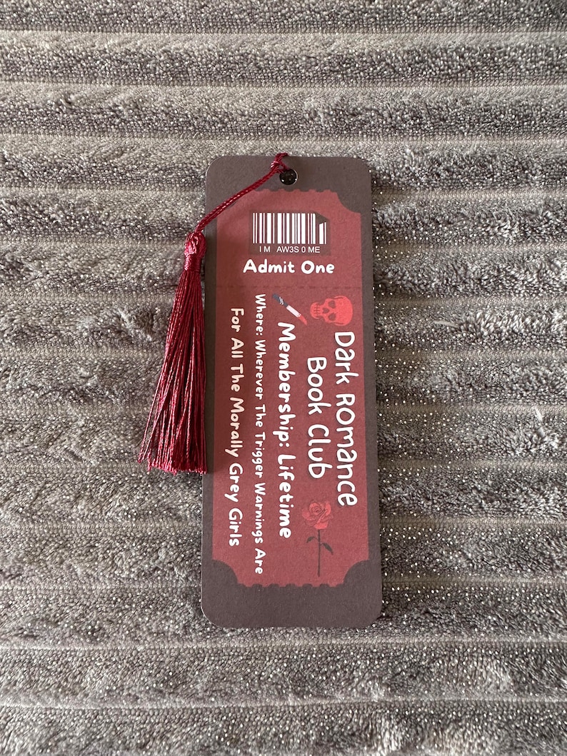 May include: A brown bookmark with a red tassel. The bookmark has a dark red background with white text that reads "Dark Romance Book Club Membership: Lifetime" and "Where: Wherever The Trigger Warnings Are For All The Morally Grey Girls".