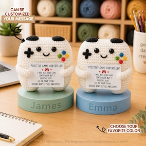 May include: Two white crocheted game controller figures with black buttons and colourful accents, each holding a card that reads: POSITIVE GAME CONTROLLER, I MAY BE A TINY GAME CONTROLLER, BUT I BELIEVE YOU, GO DO YOUR THING! YOURE NEXT LEVEL AWESOME!