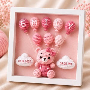 Könnte beinhalten: Ein weißer quadratischer Schattenfugenrahmen mit einem gehäkelten rosa Bären mit Schleife, umgeben von gehäkelten rosa Luftballons mit den Buchstaben E, M, I, L, Y. Zwei weiße gehäkelte Wolken tragen den Text 07.12.2027 und 09:25 PM.