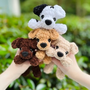 以下が含まれることがあります： 柔らかい質感の糸で作られた4匹の小さな犬のぬいぐるみ。犬は白地に黒い斑点、ダークブラウン、ライトタン、クリーム色のカラーリングです。各おもちゃには黒いプラスチック製の目と黒いステッチの鼻が付いています。