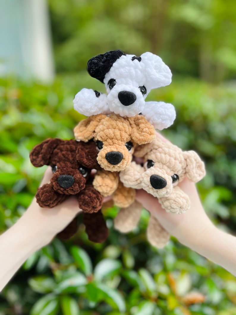 以下が含まれることがあります： 柔らかい質感の糸で作られた4匹の小さな犬のぬいぐるみ。犬は白地に黒い斑点、ダークブラウン、ライトタン、クリーム色のカラーリングです。各おもちゃには黒いプラスチック製の目と黒いステッチの鼻が付いています。