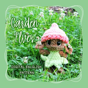 May include: A handmade crochet garden elf doll with a pink hat and green outfit, set against a backdrop of green grass and white flowers. The image includes the text "Garden Elves" and "DIGITAL ENGLISH PATTERN".