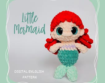May include: A handmade crochet mermaid doll with red hair, large blue eyes, and a teal tail. The doll has a cream-colored face and body, with a teal and purple bodice. The image includes the text "Little Mermaid" and "DIGITAL ENLGLISH PATTERN".