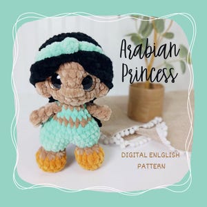 Op de afbeelding: Een handgemaakte gehaakte pop in de vorm van een Arabische prinses. De pop heeft een zwarte en mintgroene hoofdbedekking, grote ogen en een mintgroene en bruinbeige outfit. De tekst "Arabian Princess" en "DIGITAL ENLGLISH PATTERN" is zichtbaar.