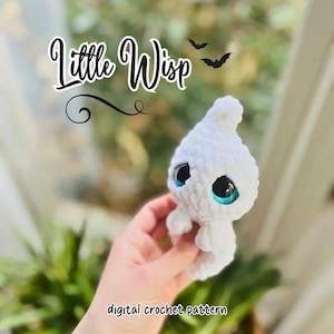 Könnte beinhalten: Ein weißes gehäkeltes Plüschtier mit großen, glänzenden blauen Augen und einer spitzen Oberseite. Der Text Little Wisp steht in schwarzer Schreibschrift über dem Spielzeug, begleitet von zwei kleinen schwarzen Fledermaussilhouetten.