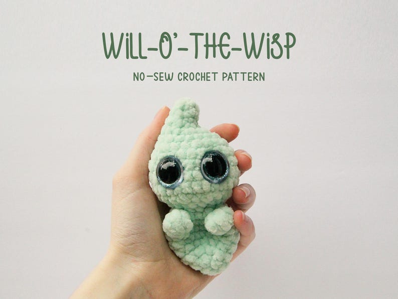Puede incluir: Un fantasma verde de crochet con grandes ojos negros. El fantasma est&aacute; siendo sostenido en una mano. El texto "WILL-O'-THE-WISP NO-SEW CROCHET PATTERN" est&aacute; por encima del fantasma.