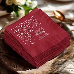 Può includere: Una pila di tovaglioli di carta bordeaux con un design a coriandoli argentati e la scritta "Happy Birthday". I tovaglioli includono anche il testo "Maria Grace! Classy, Sassy & 45!" nell'angolo in basso a destra.